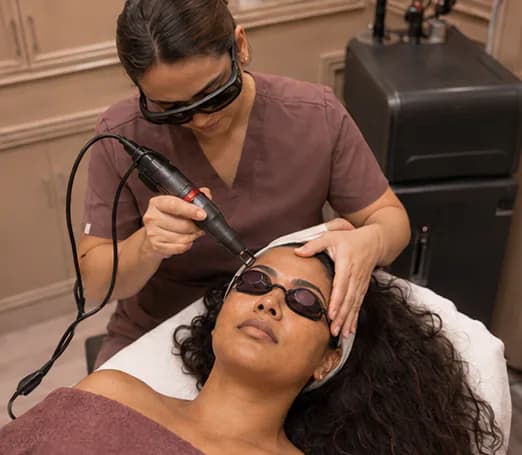 Aesthetician performing a Pico laser facial treatment with protective eyewear